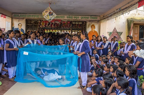 Group of school girls show how to use bed nets