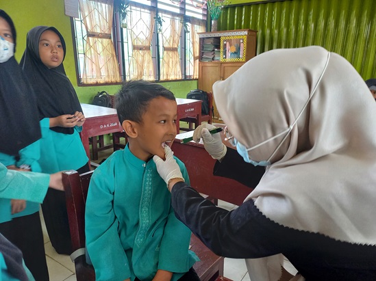 An adult with two children brushing their teeth.