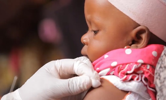 An infant gets prepared for a shot.