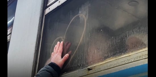 Child hand touching a heart shape on a bus window