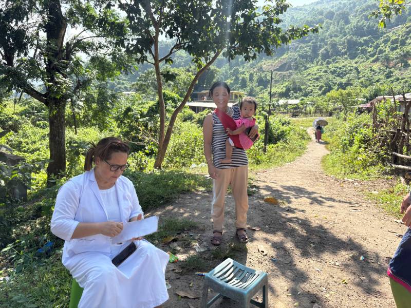 An auxiliary nurse midwife checks a child’s immunization card during an outreach session in Pachan Morang Colony, East Kameng, Arunachal Pradesh.