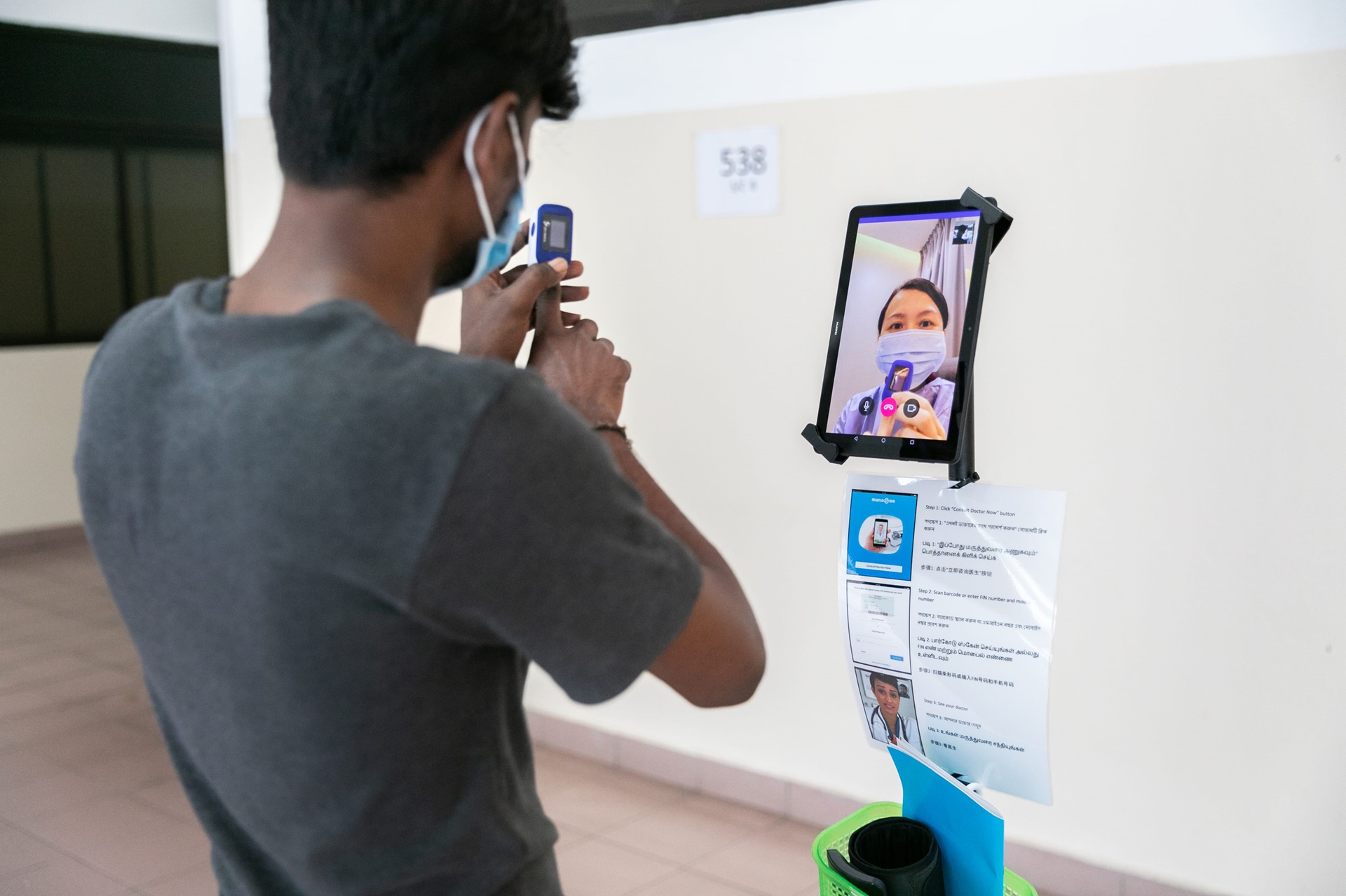 Photo 1 Photo of a man in Singapore having a video conversation on a tablet with a medical worker.