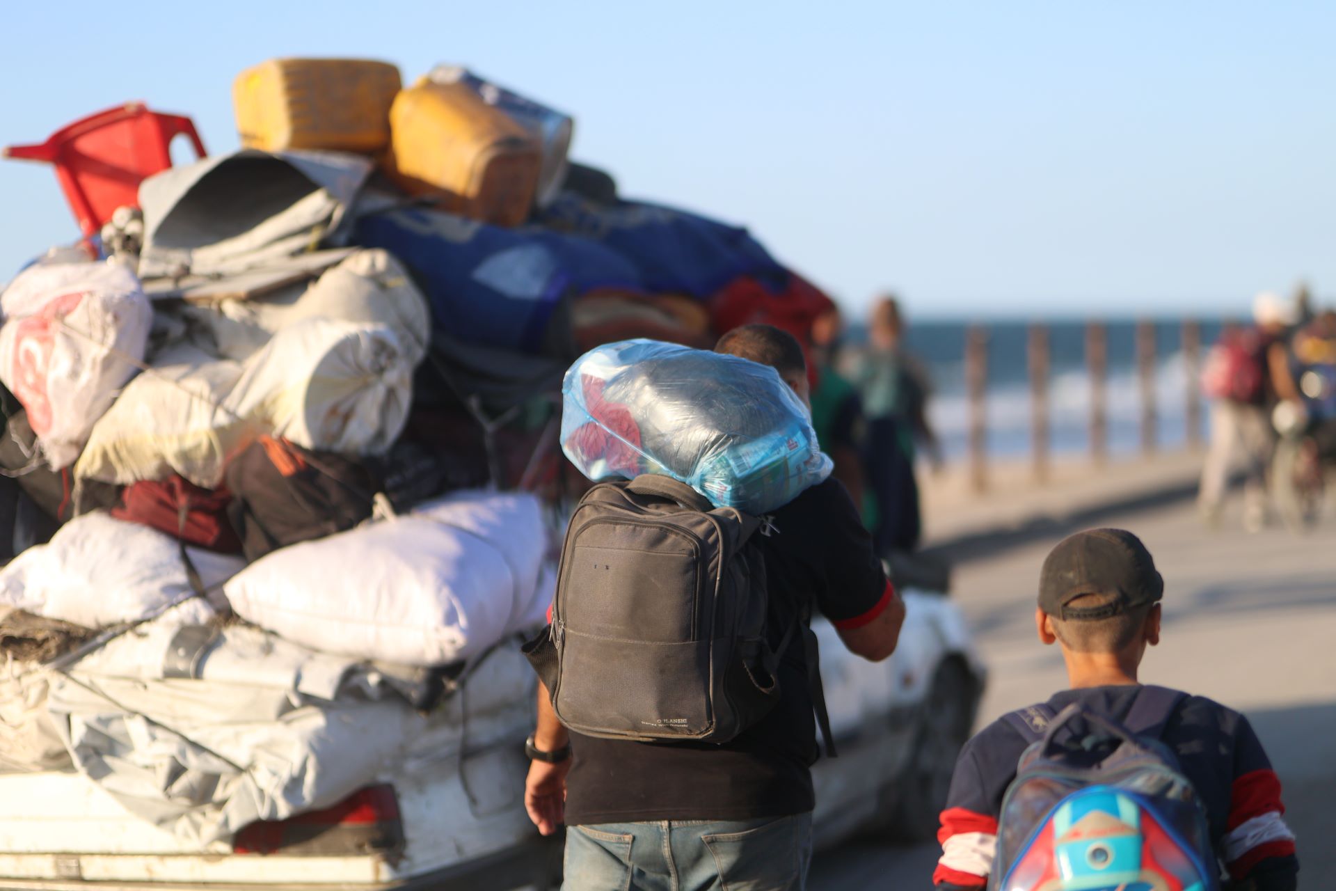 A man and box carrying rucksacks beside a heavily-loaded vehicle