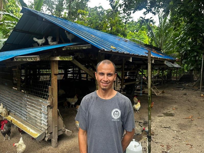 A person standing in front of a chicken coop on a poultry farm.