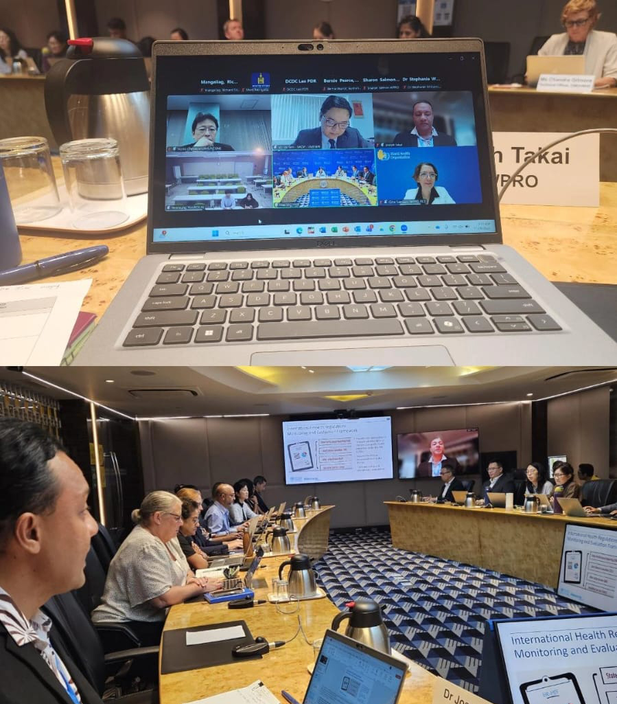 A panel of speakers at a meeting with a speaker in the foreground presenting slides