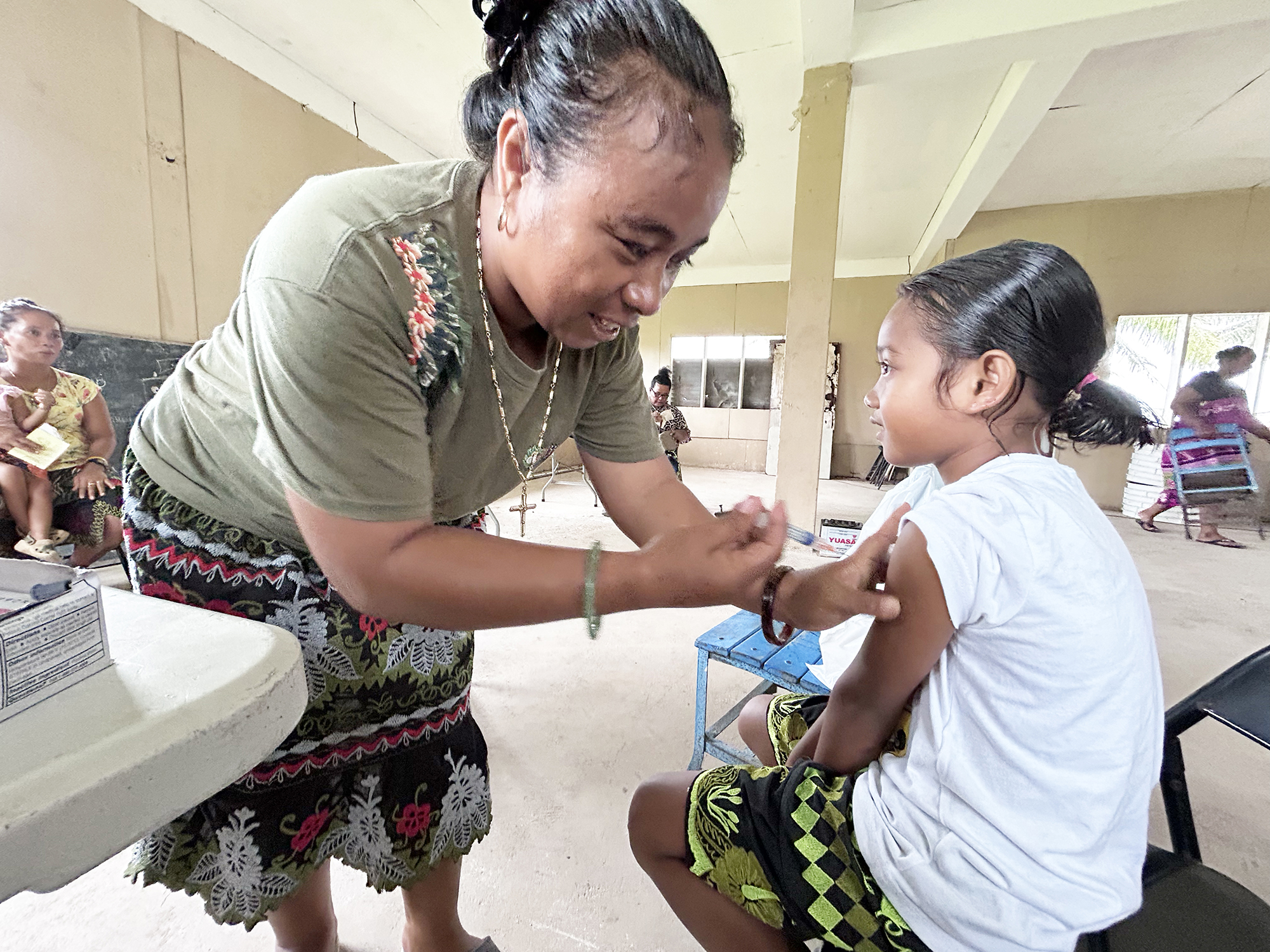A woman administers a vaccine to a child