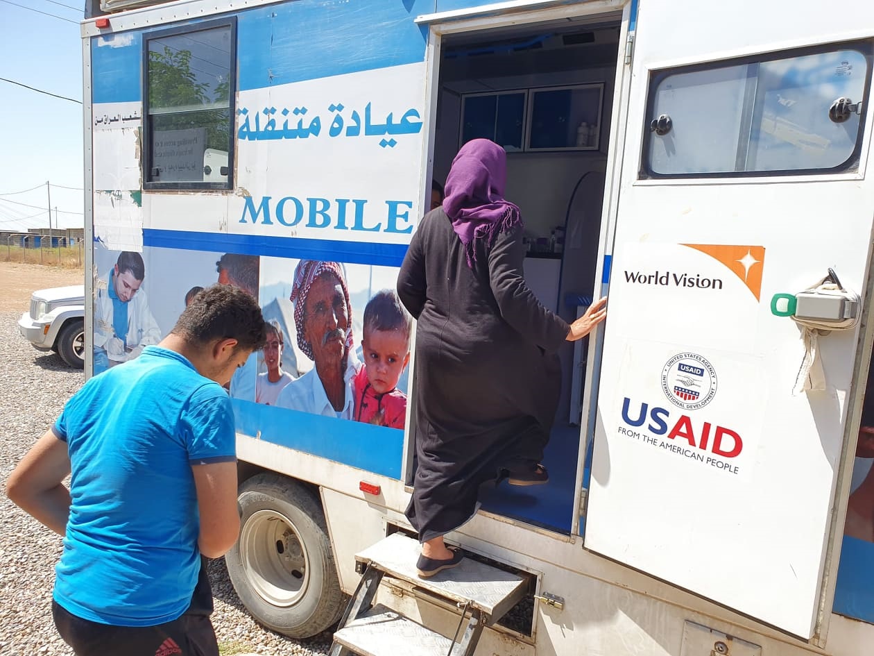 Iraq mobile clinic A woman enters a mobile health clinic whilst as a man is waiting next in line.
