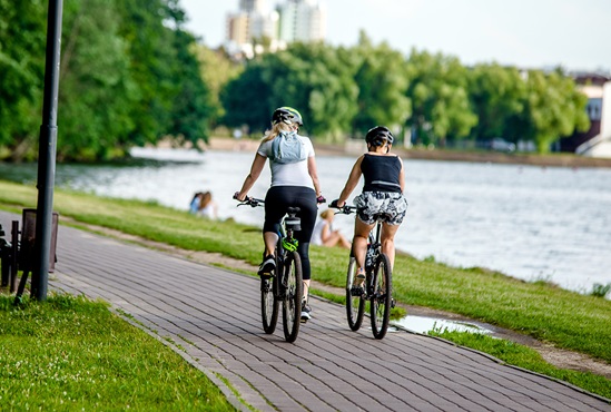 urban green and blue spaces two people cycling by a river