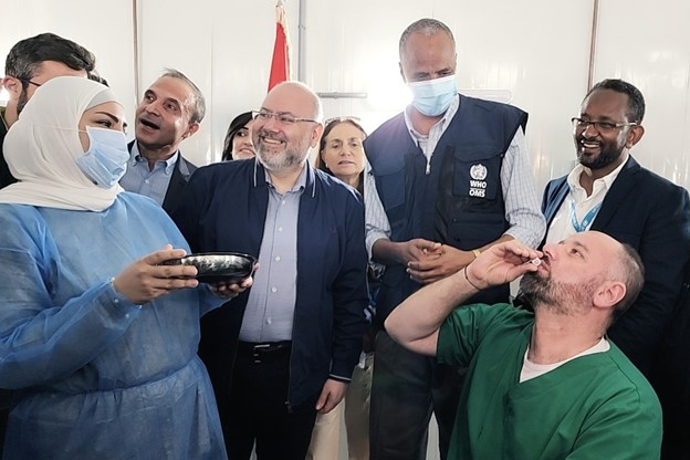 People gathered in a room whereas one man is taking an oral cholera vaccine