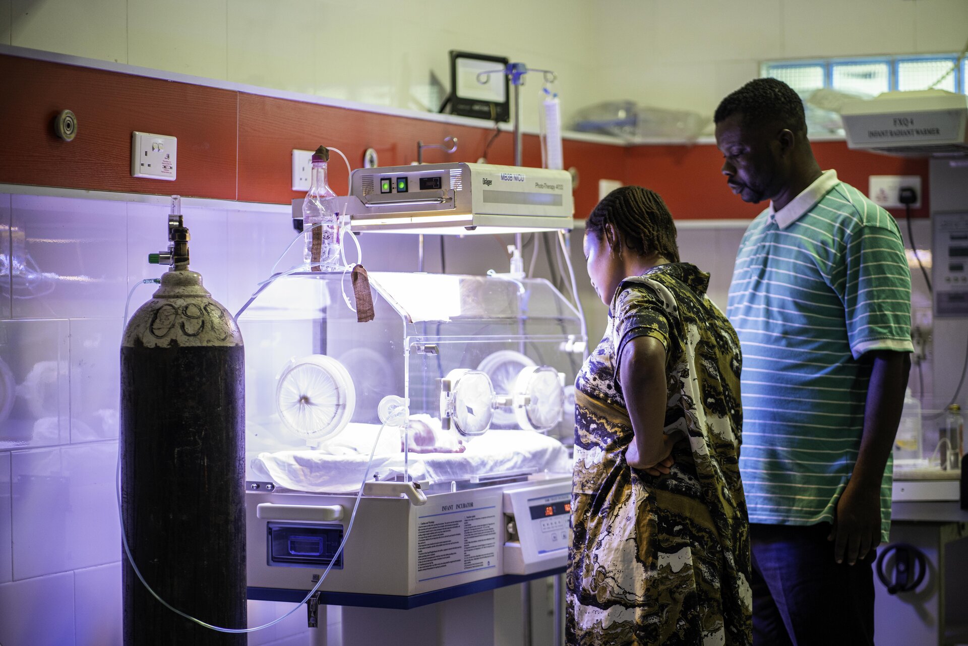 New born receives additional care in incubator with family watching over