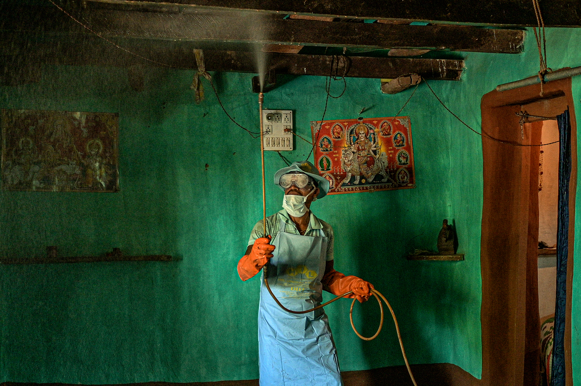 Man spraying insecticide inside a house