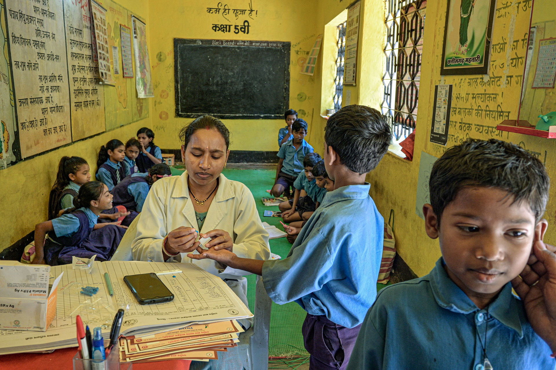 Health worker testing a school boy for malaria