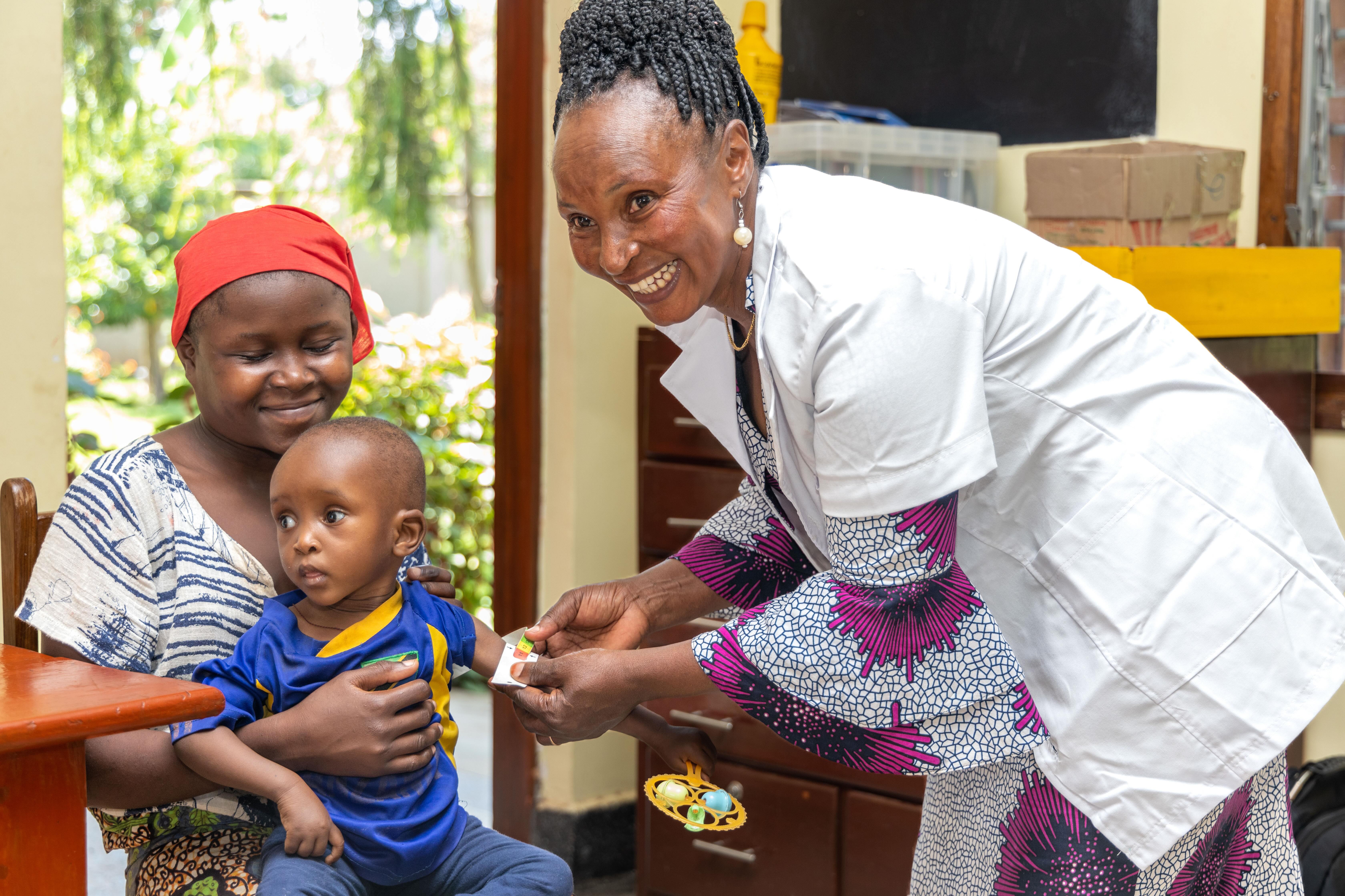 A mother holding her two-year-old daughter for a nutrition test in a community clinic in Tanzania