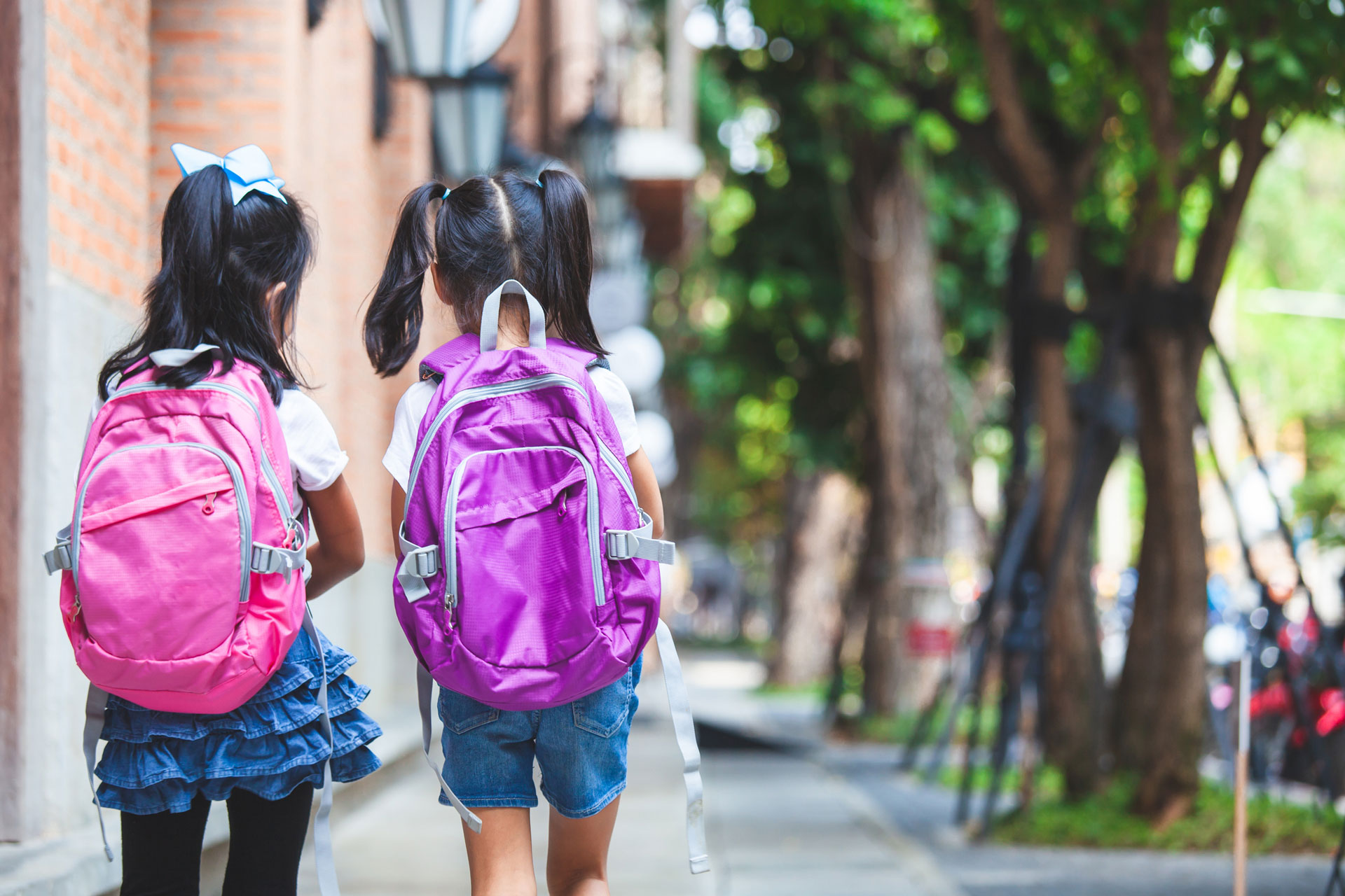 Two little girls walking wearing school bags
