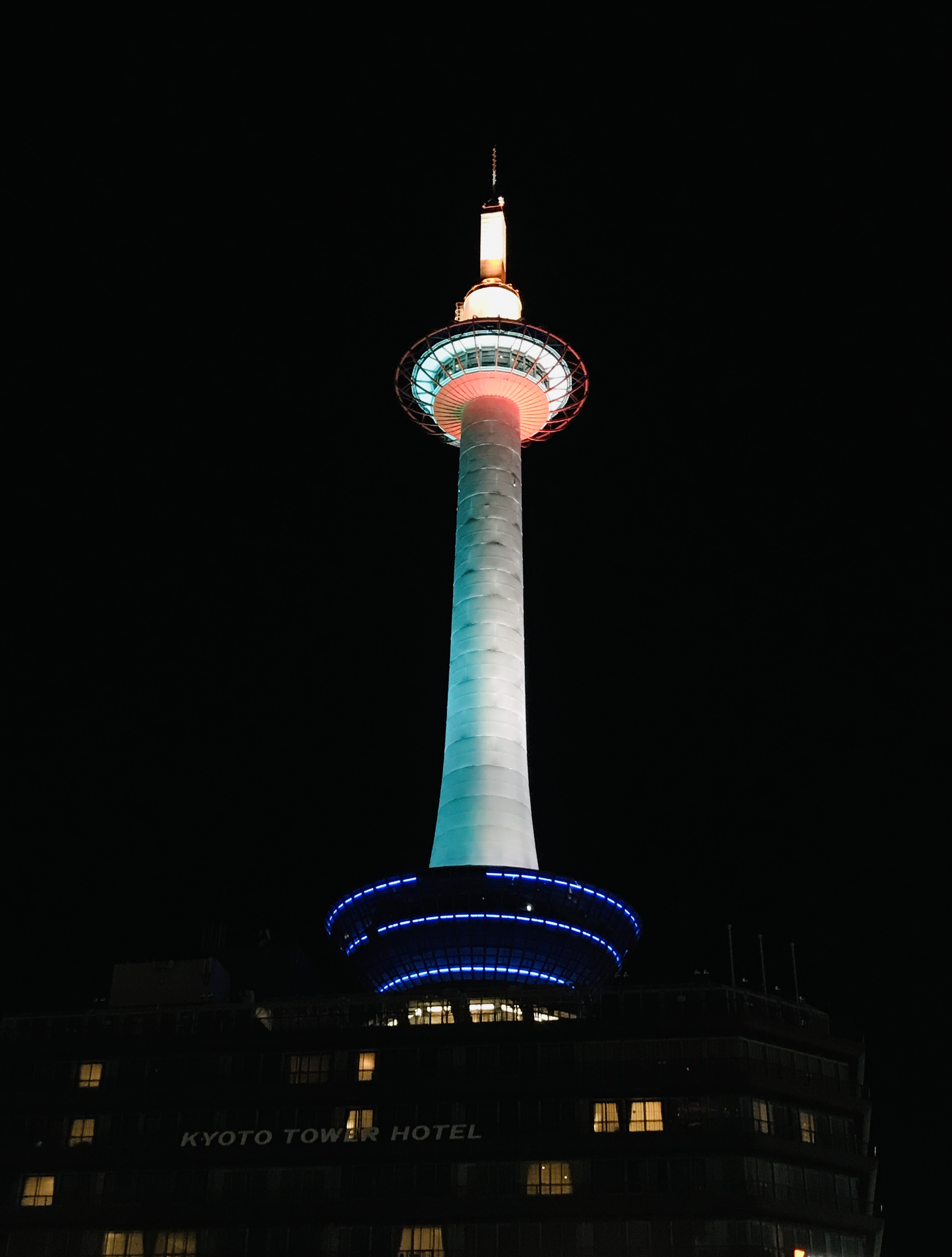 Kyoto Tower at night, lit with red, green, and blue lights above the Kyoto Tower Hotel.