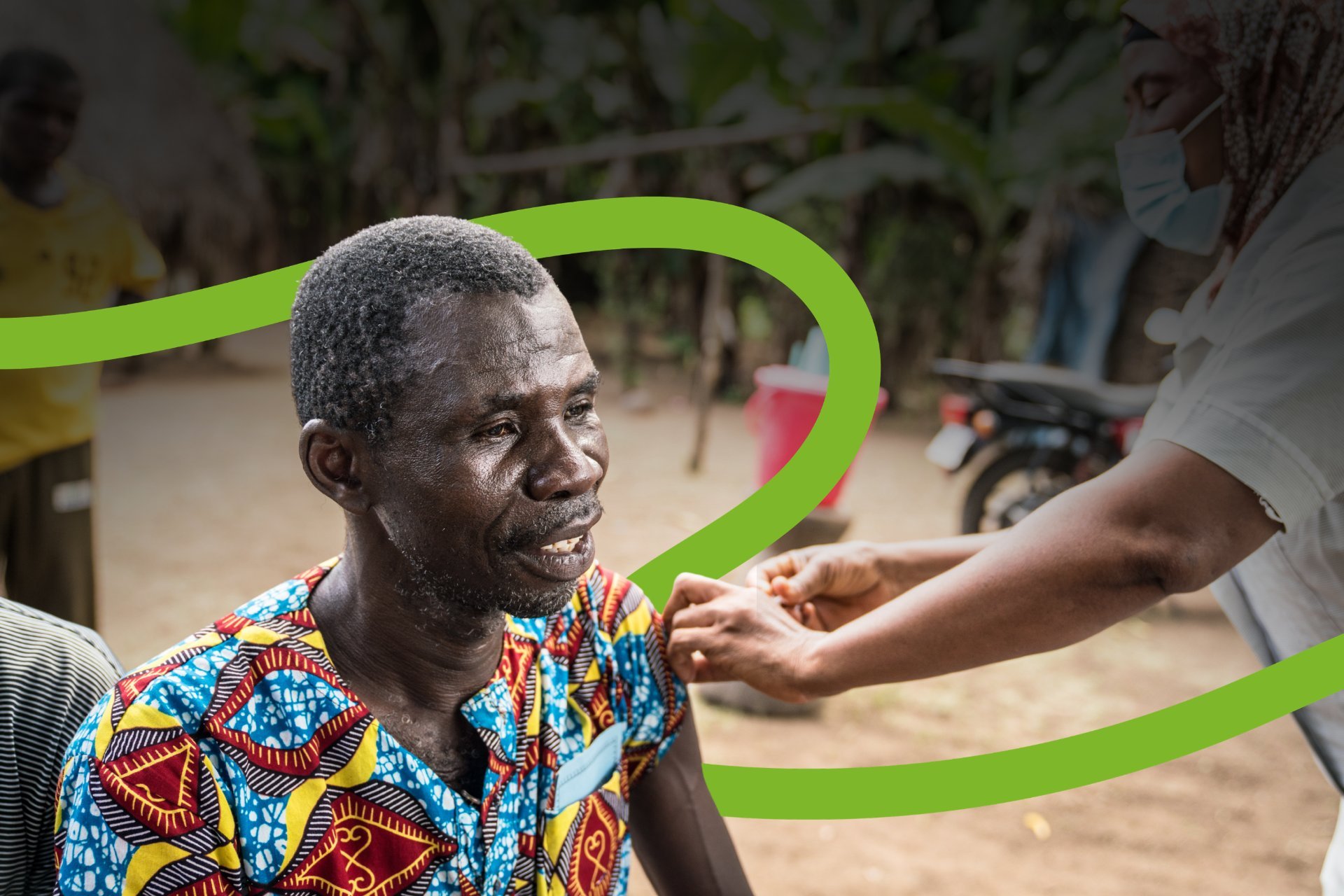 A person receives a vaccination from a health worker, with a green illustrated wave line across the image.