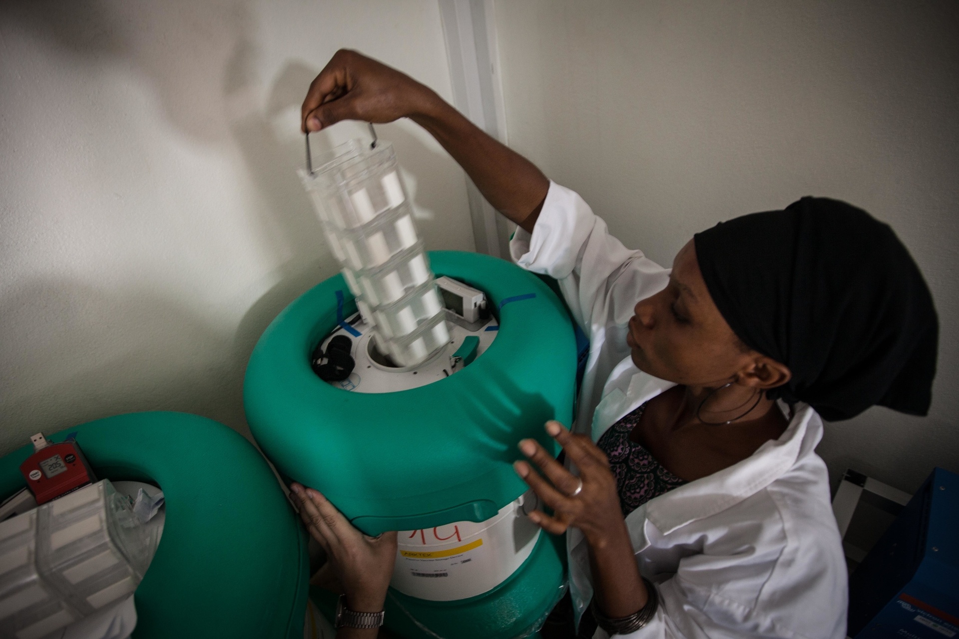 A lab technician is inserting a vaccine core into the storage device.