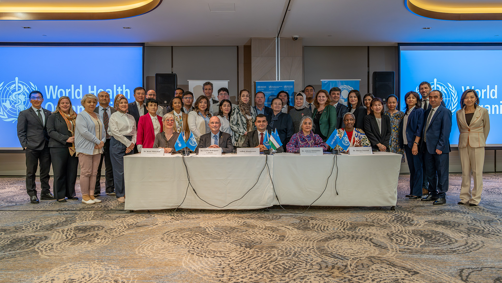 A group of people sitting and standing behind a table posing for the photograph.