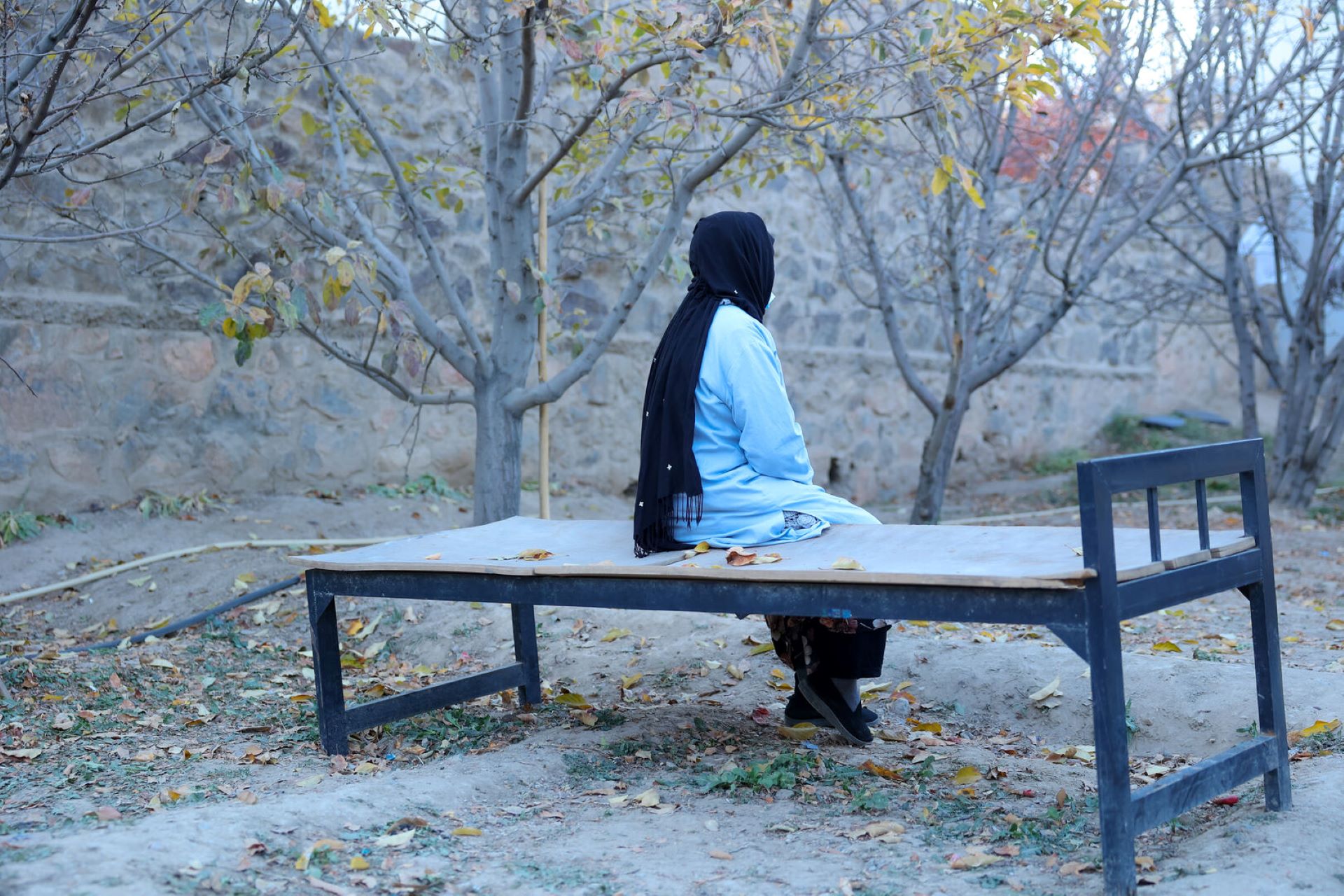 Woman sitting on a bed without a mattress outdoors