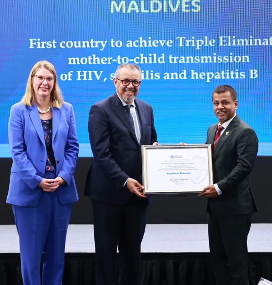 A man in suit handing a certificate to another man in suit, and a lady in 2-piece suit standing on the left.