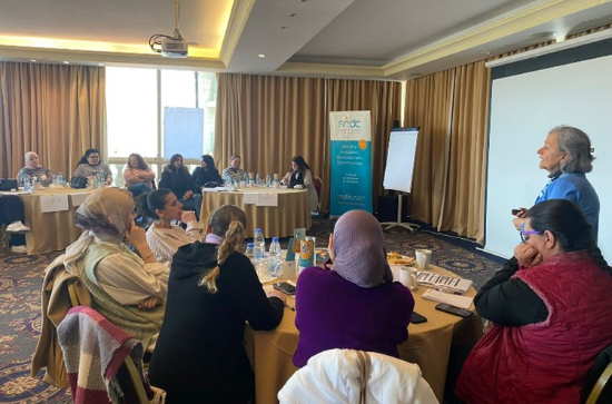 Group of individuals sitting at tables during a meeting, one participant standing addressed the audience