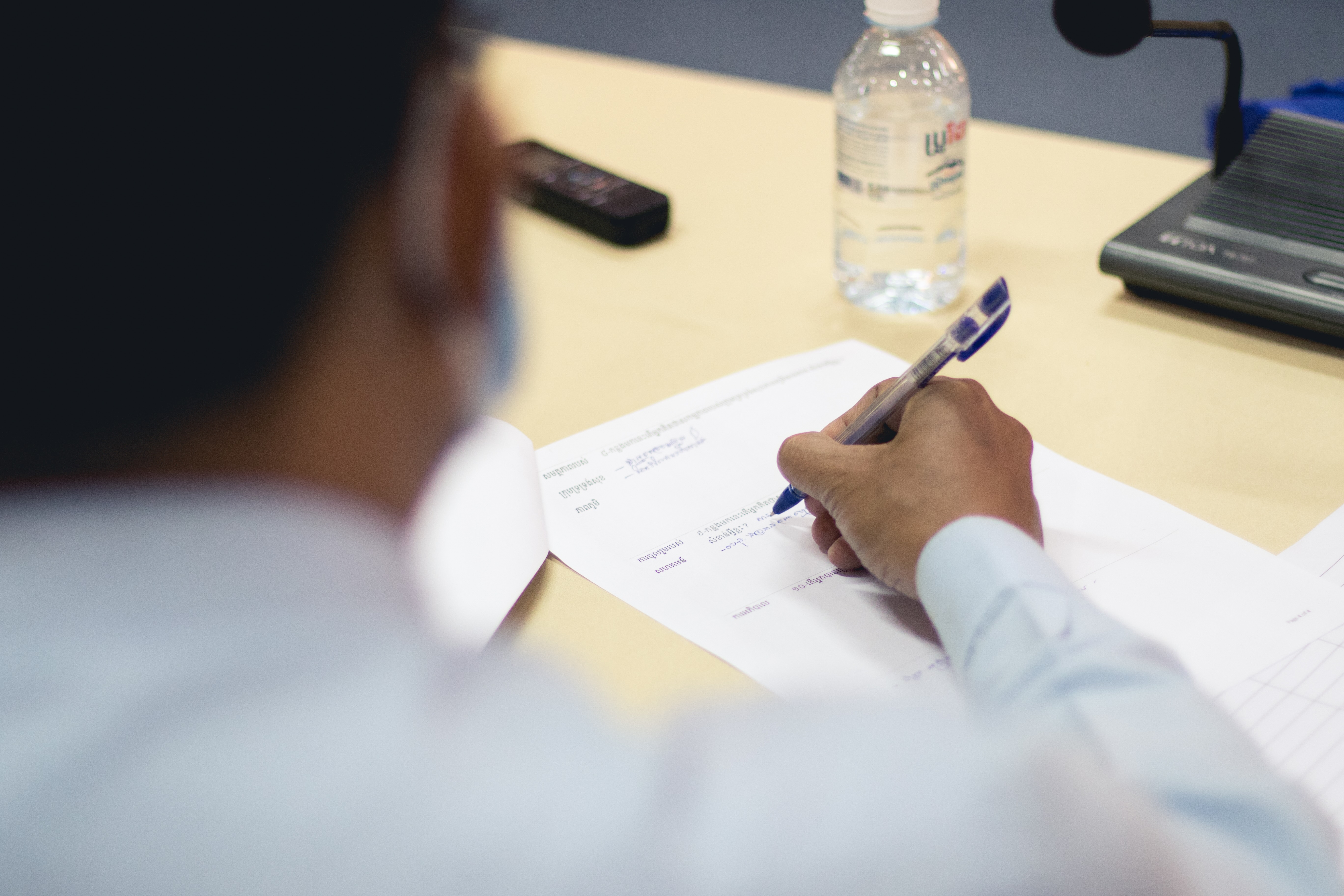 Man with a white blouse writing on a piece of paper