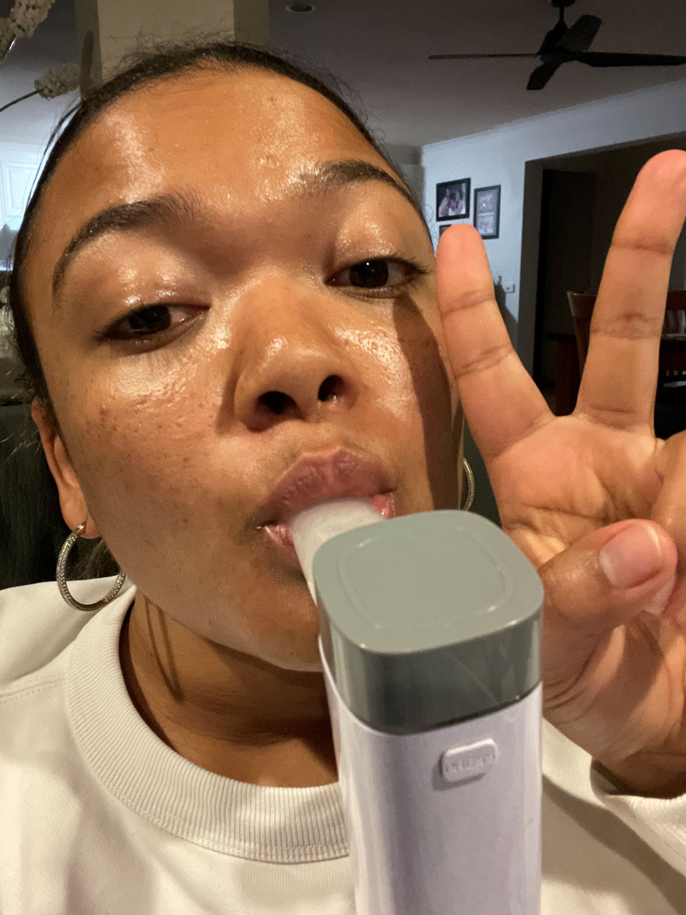 A person using a handheld medical device.  She is making a peace sign with her fingers while engaging with the device.