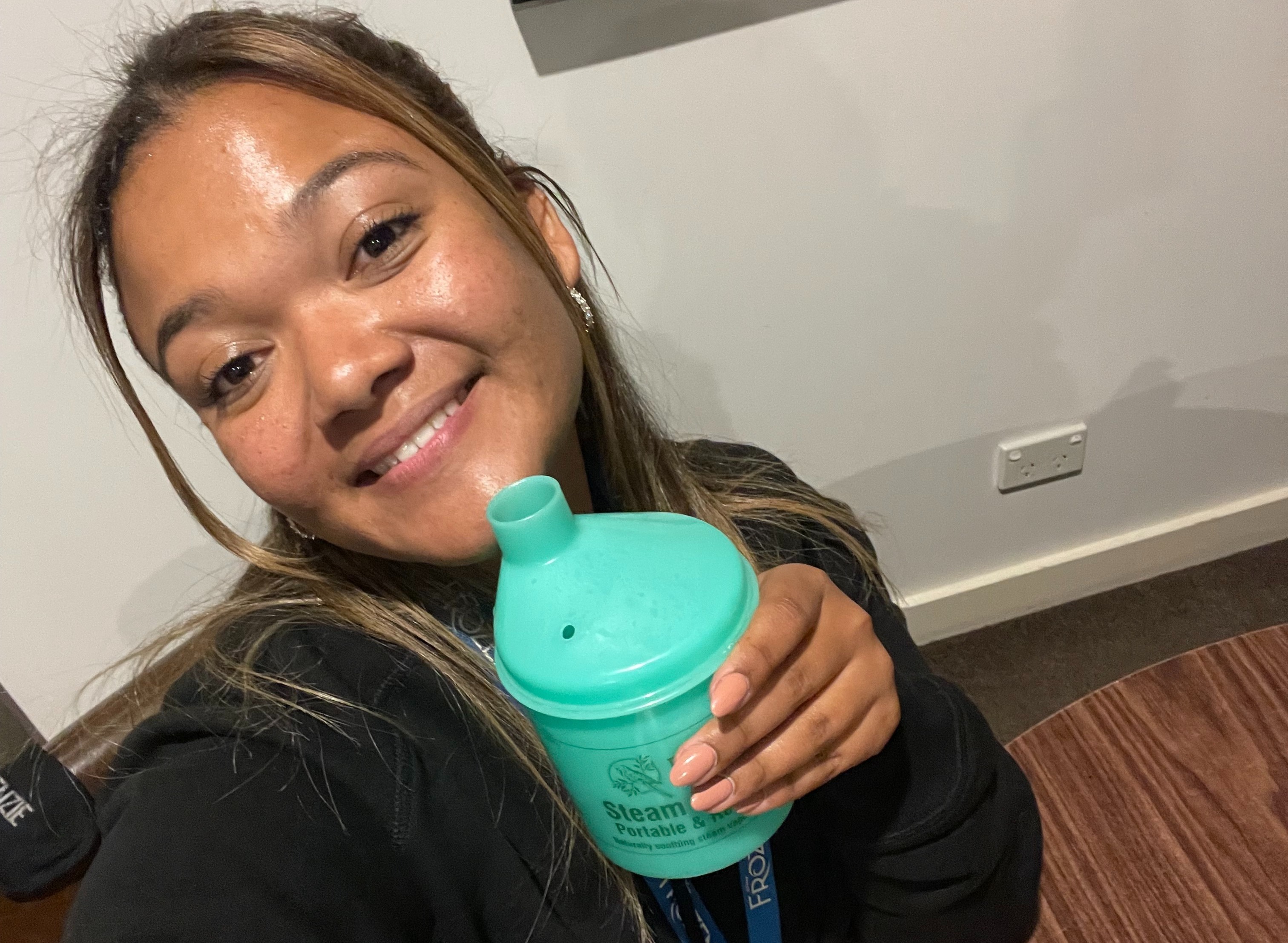 A young woman is smiling while holding a steam cup