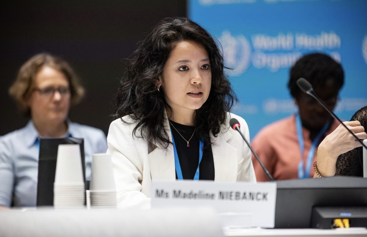Maddi sitting down in a meeting room. Two females are seen sitting on the background
