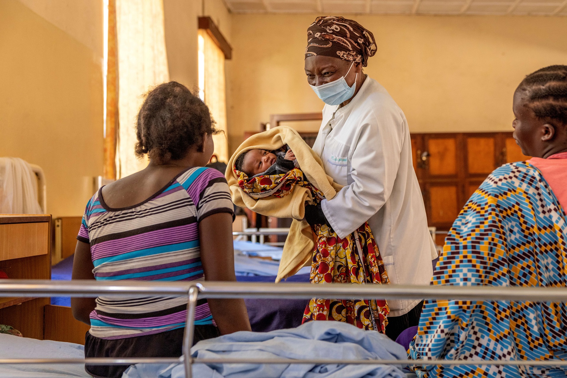 A midwife carrying a baby in a hospital setting.