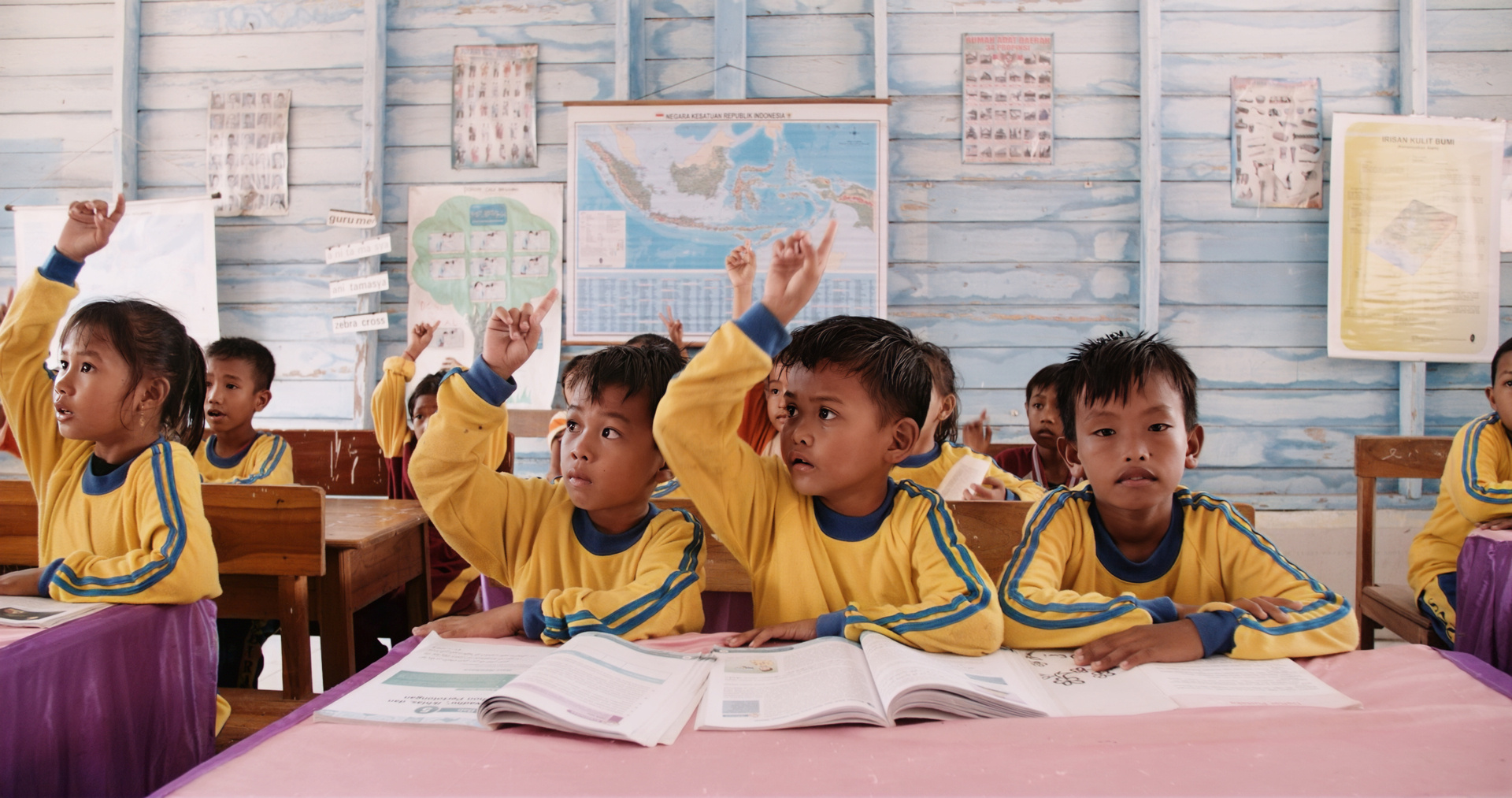 Children at an elementary school raise their hands to answer a question