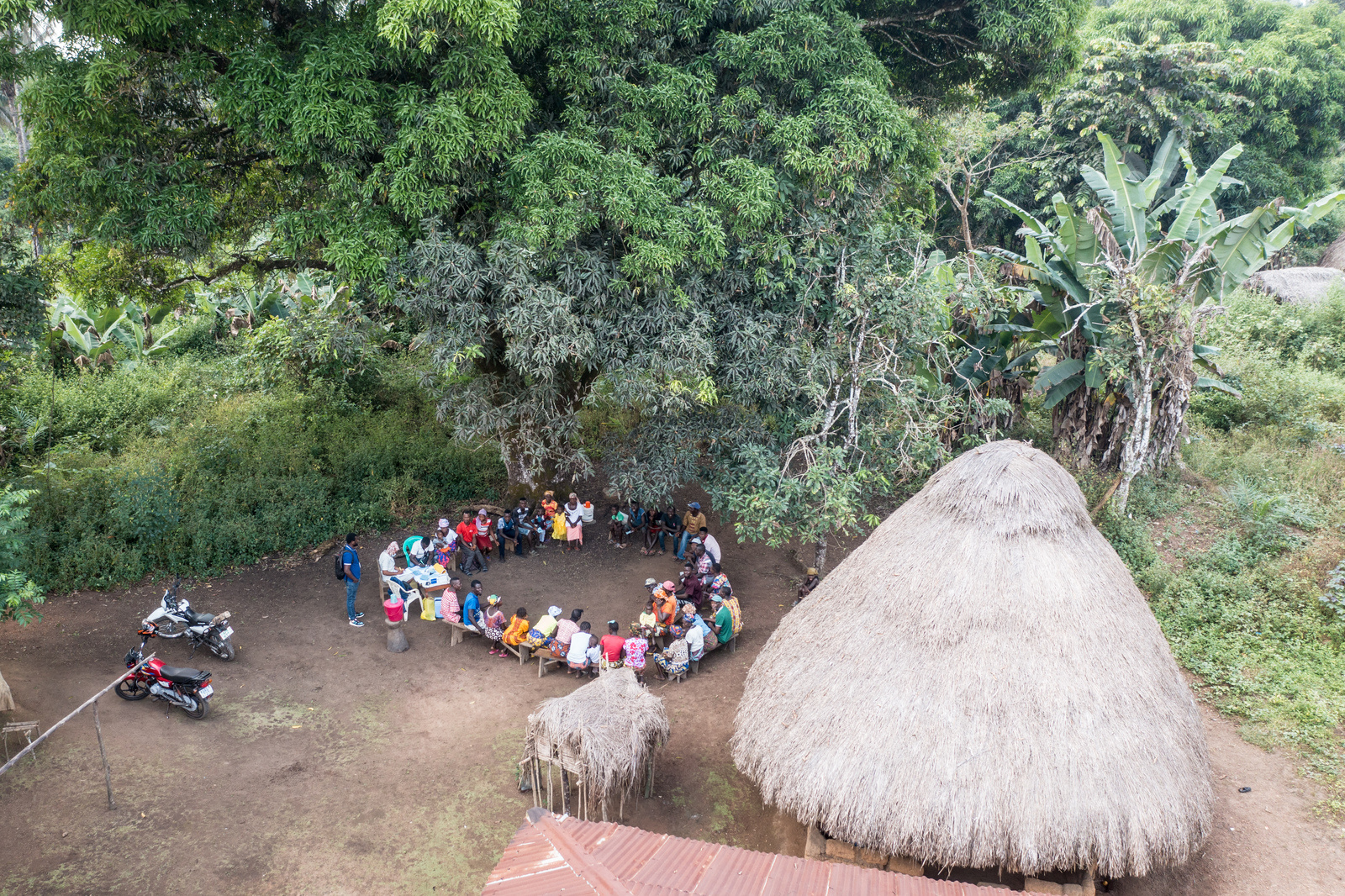 Residents of the village of Makontakay, Sierra Leone, meet under a mango tree to be vaccinated against COVID-19 from a mobile health team on 8 December 2022.