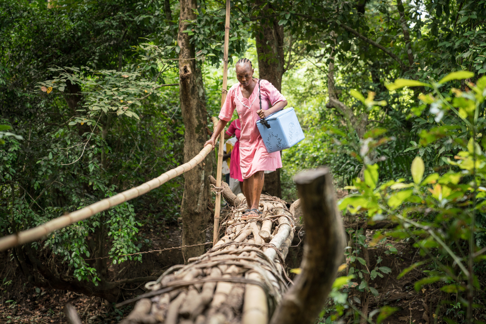 Nurse Isha crosses a bridge to reach the remote village of Mansunthu to conduct a mobile COVID-19 vaccine clinic on 7 December 2022.