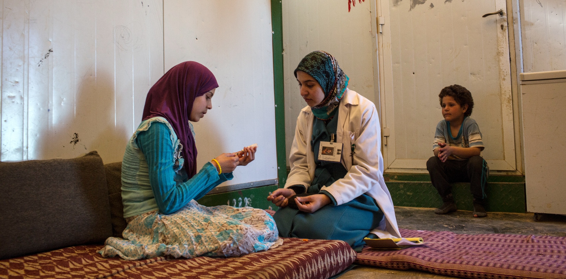 A health-care worker shows a young woman how to administer an insulin shot.