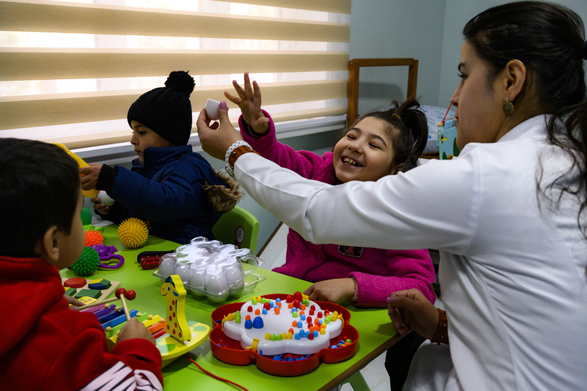 3 children with a health worker during their rehabilitation session