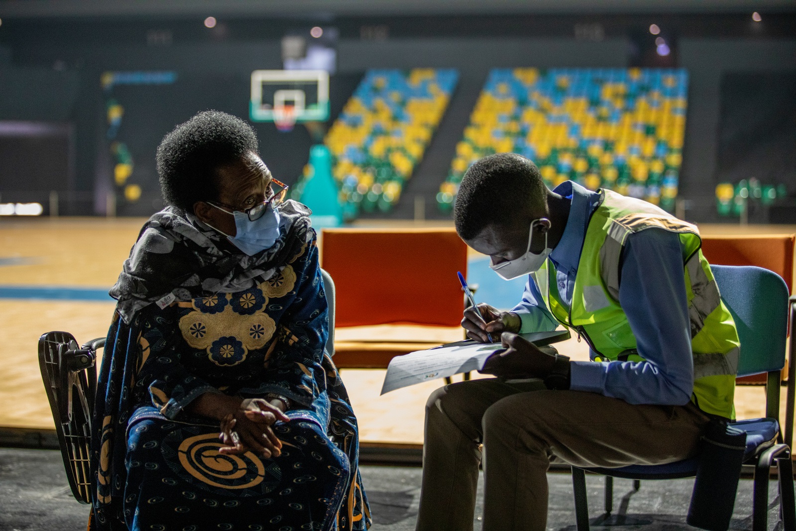 F98A2901 a volunteer helps a woman fill out paperwork before her COVID-19 vaccine in Rwanda.