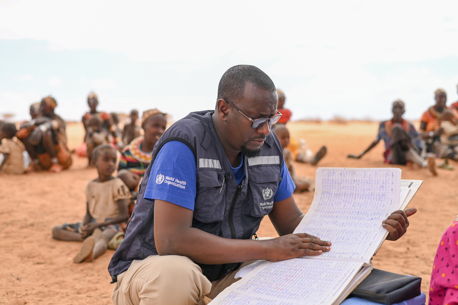 On 20 September 2022, WHO's Dr Adam Haj looks at medical records during a health screening by a mobile team in Korr, Marsabit.