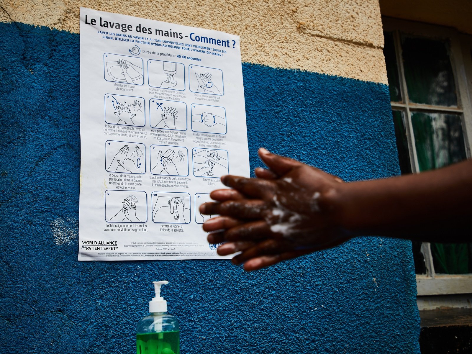 Poster2_tb Person washing hands with instructional poster in the background