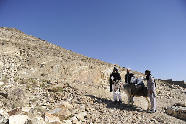 Three men walk up a rocky hill.