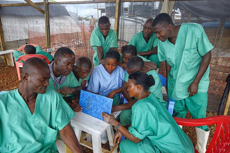 Health workers in Africa huddled around a laptop, as part of their work around Ebola