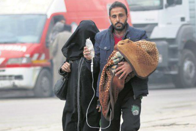 A man walks carrying a child in one arm and an IV drip in the other.