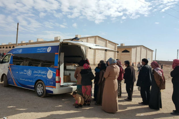 Two aid workers examine and care for a leg wound.