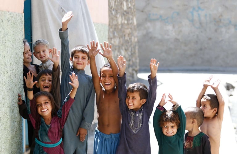 Young boys and girls raise their hands to show marks of vaccination against polio, in Afghanistan