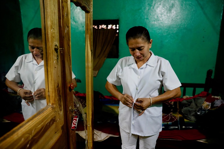 A nurse buttoning her shirt in her apartment in Los Brasiles, Nicaragua