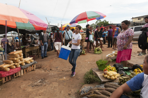 A young woman carries a cooler of vaccines through a market in Tabatinga, Brazil