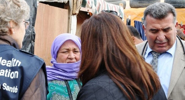 WHO staff listening to displaced Syrian woman talking about health needs.