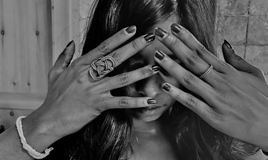 A young woman covering her face with her hands.