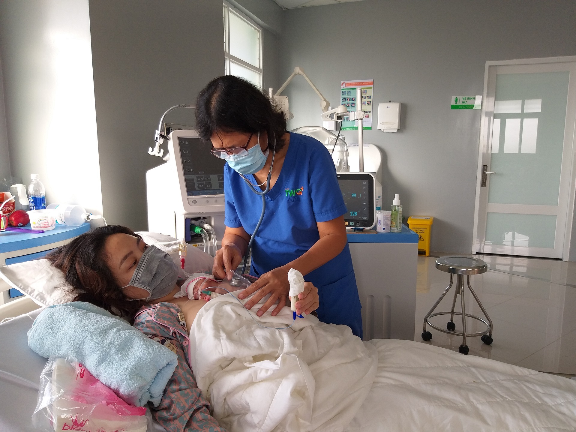 A healthcare worker examines a mother and her newborn A healthcare worker and a newborn in a hospital setting.