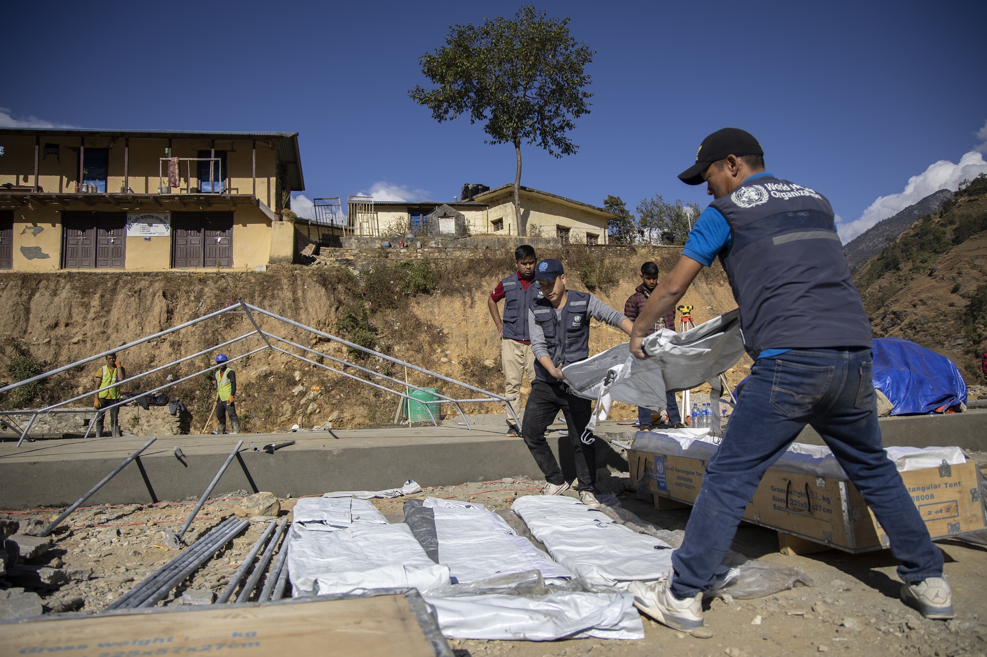 WHO staff unloading a rectangular tent provided by WHO Nepal at the earthquake-affected Jajarkot, Karnali Province, Nepal