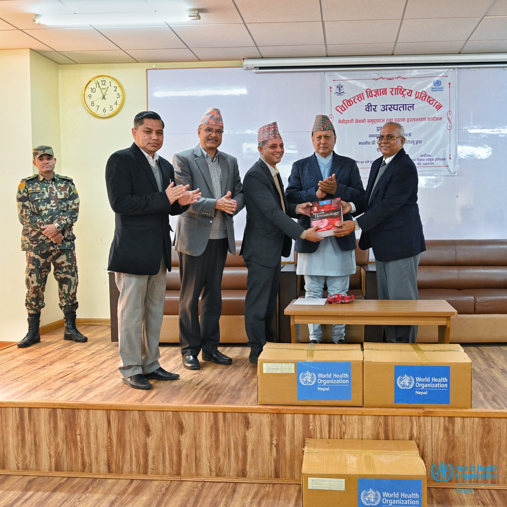 WHO Representative to Nepal (right) handing over medical books to a representative from the National Academy of Medical Sciences, Bagmati Province, Nepal